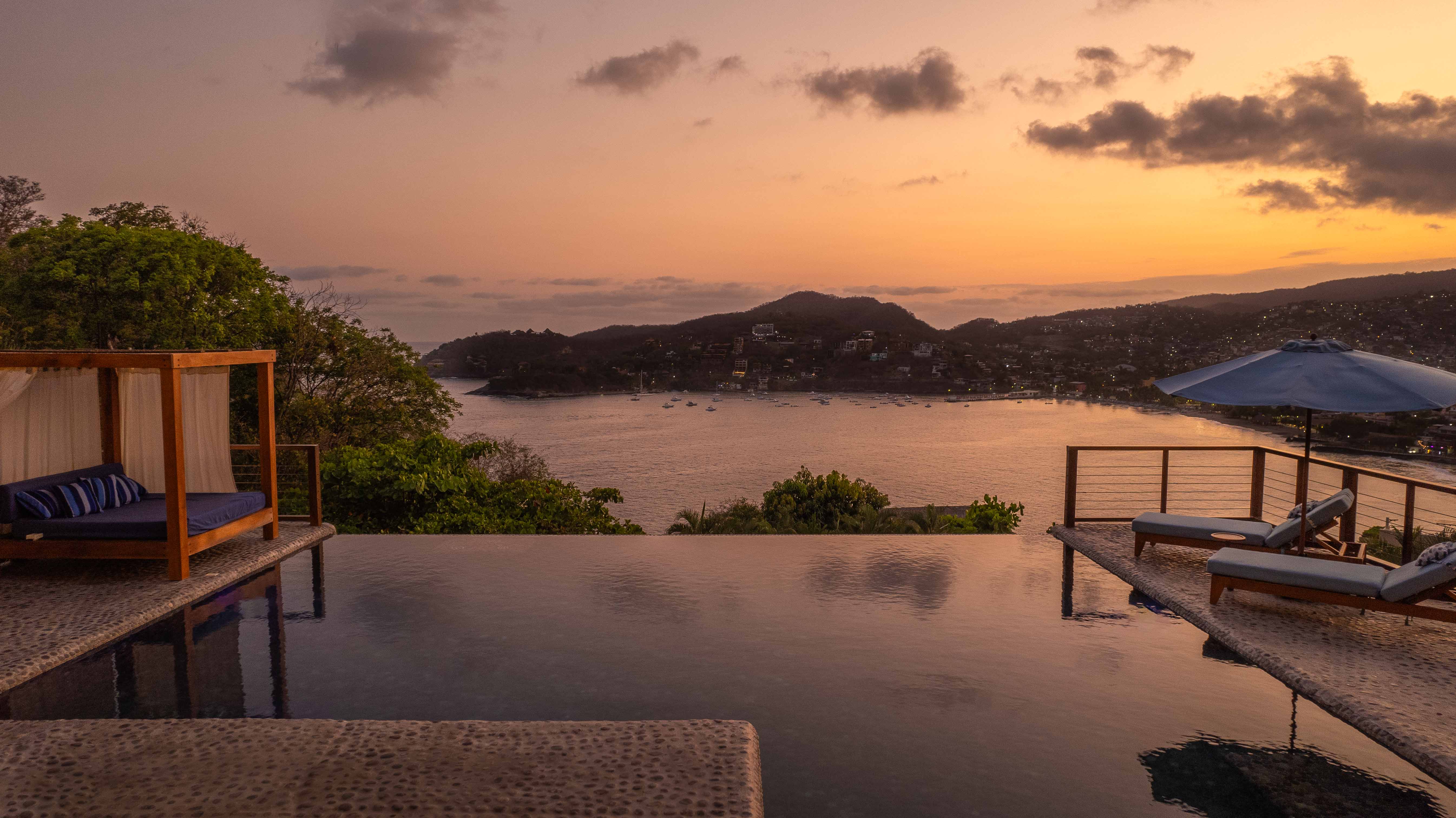 Luxury residence with pool, lounge furniture and Zihuatanejo Bay views at sunset