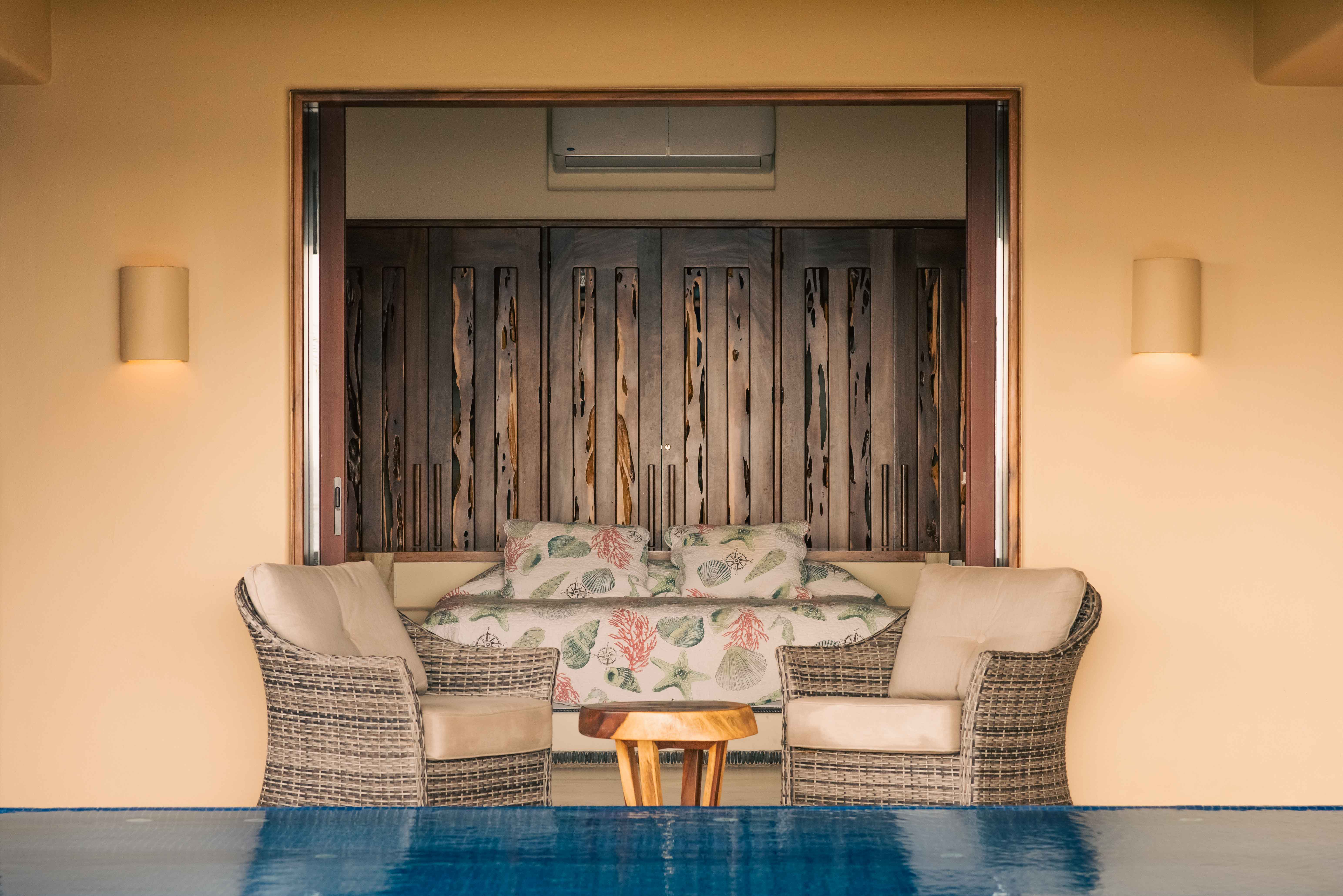 Symmetrical view through a bedroom toward a pool with chairs and architectural lines