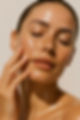 woman with glowing skin no makeup touching her cheek with her eyes closed