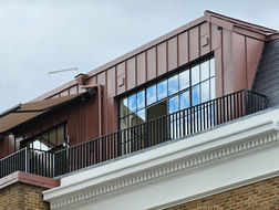 Glazed rooftop extension with metal cladding and terrace