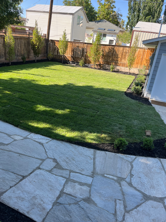 Fresh sod lawn installation with stone patio hardscaping in Draper Utah