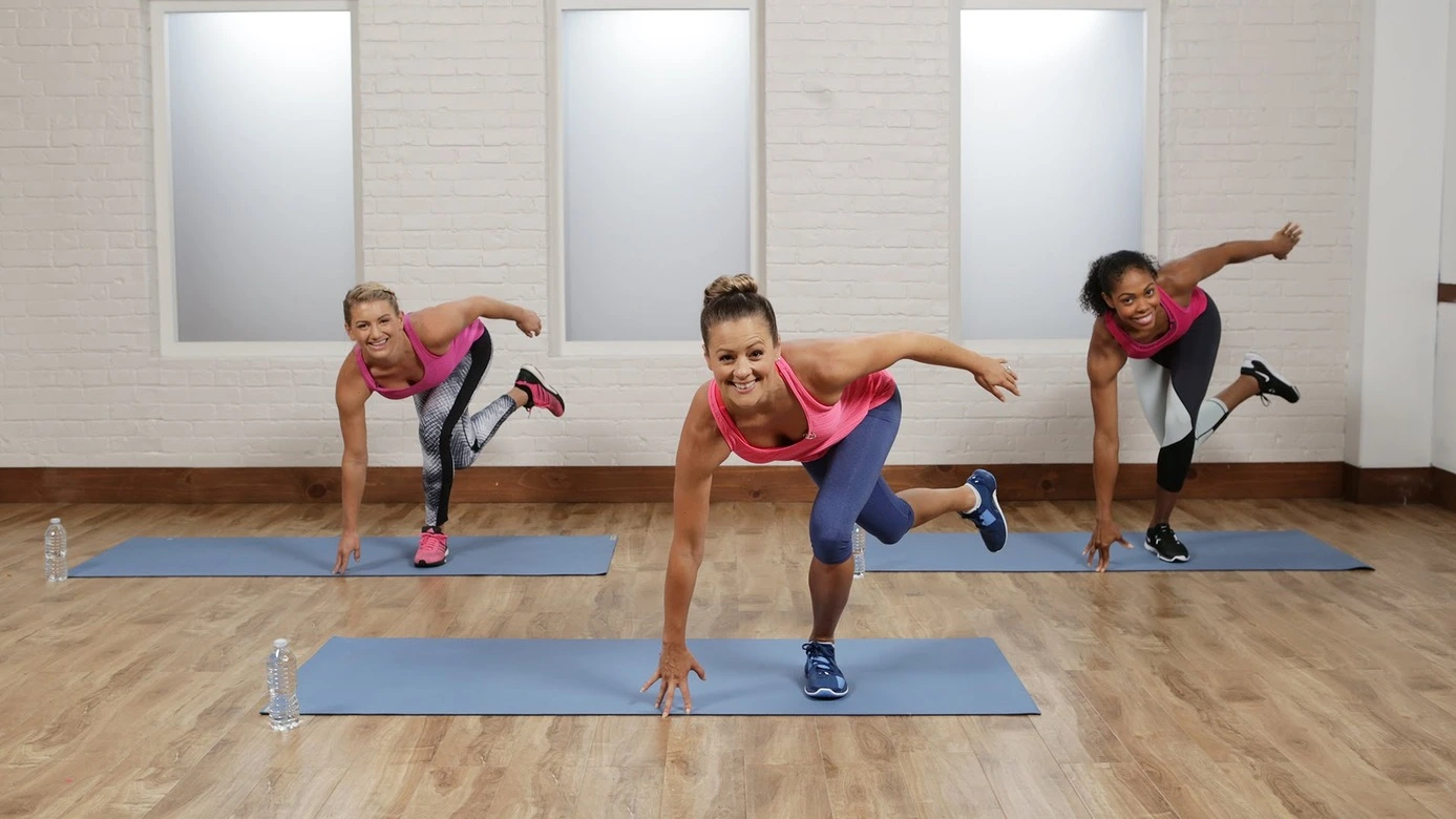 Dans un studio d'entraînement, trois femmes se consacrent à des séances de pliométrie pour améliorer leur mobilité et leur endurance. Chacune d'entre elles ont une bouteille d'eau, témoignant de leur hydratation et de leur engagement envers leur santé.