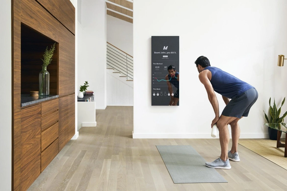 Dans sa maison, un homme se trouve devant son miroir intelligent, où ses données personnelles sont affichées. Il utilise cet outil pour suivre son évolution et surveiller ses paramètres de santé tels que le poids, la fréquence cardiaque et d'autres indicateurs.