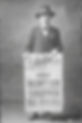 1914 postcard showing a man (Vale Rawlings) standing behind a newspaper billboard with the headline, 'How Burton Cheered Vale Rawlings'.