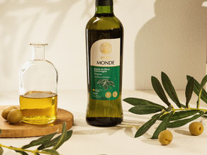Garrafa de azeite de oliva extra virgem MONDE 500 ml, com azeitonas e ramos de oliveira ao lado.