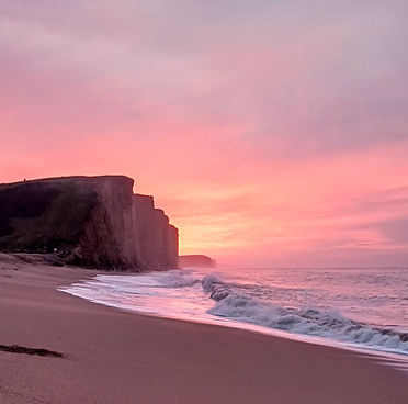early morning pink sky over sea in west bay, dorset