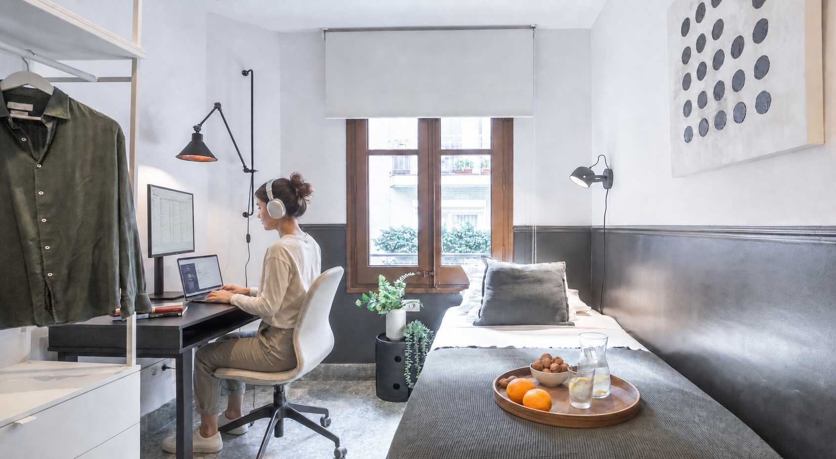 Woman working with a laptop, monitor and headphones in Haaus Escorial 201 room in Barcelona.
