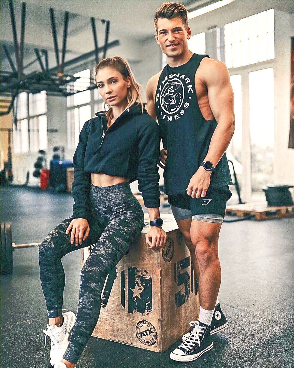 Fit man and woman in athletic wear posing in a gym