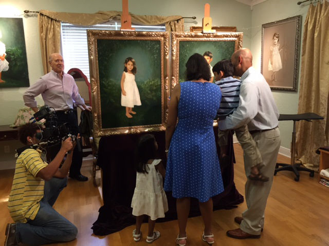 The parents and their children are leaning into the children's oil portraits deep in conversation about them.