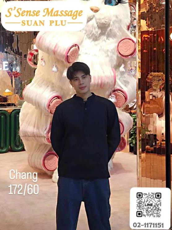 身穿黑色上衣的男性站在一隻巨型白色粉紅色調毛絨熊公仔前，上方清晰可見「S'Sense Massage Suan Plu」標誌。圖中附有QR碼及文字「Chang 172/60」。整體氛圍輕鬆有趣、親切迷人。