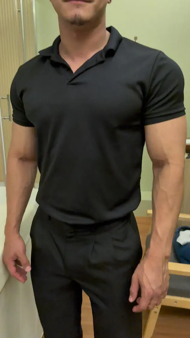 黒いシャツとパンツを着た男性がマッサージスパの部屋に立っており、マッサージ療法の歴史を象徴する「SunJi」を表しています。