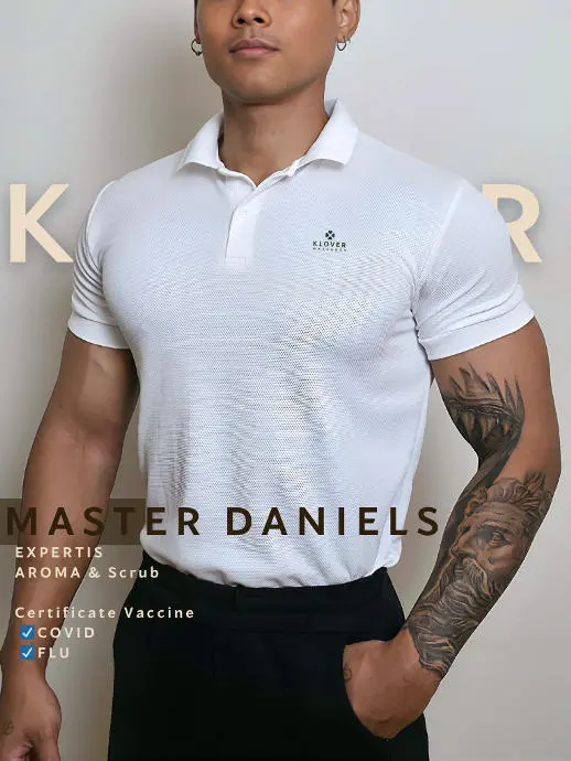 A man wearing a white polo shirt and black pants stands confidently, showcasing a casual yet polished look