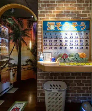 沖繩發展場淚光閃閃的入口處，設有衛生間、水槽、垃圾桶和棕櫚樹圖片