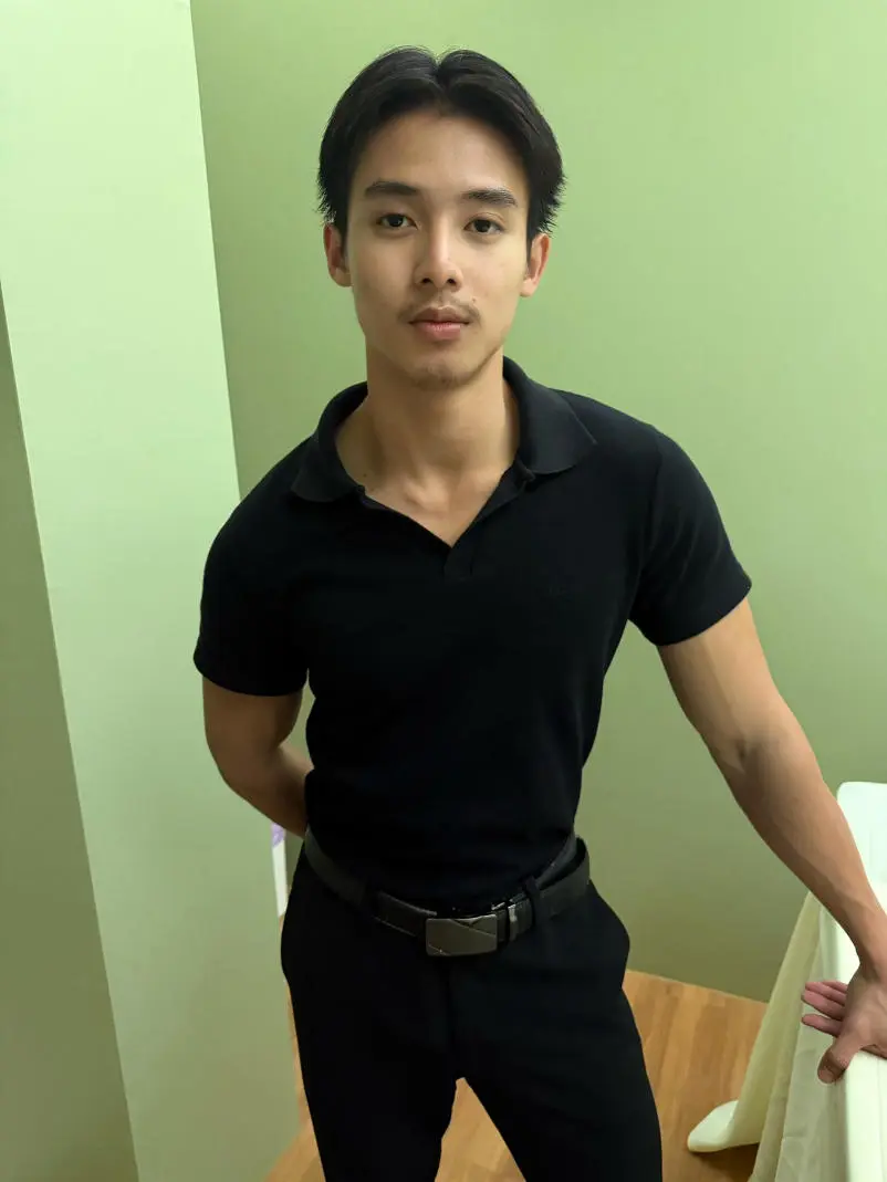 黒いシャツとパンツを着た若い男性が立っており、マッサージサービスをアピールしています。