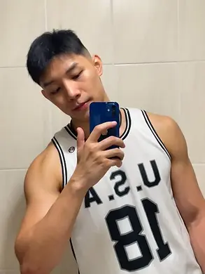 In Taipei, a man in a USA jersey smiles, snapping a selfie in the vibrant setting of a gay massage parlor