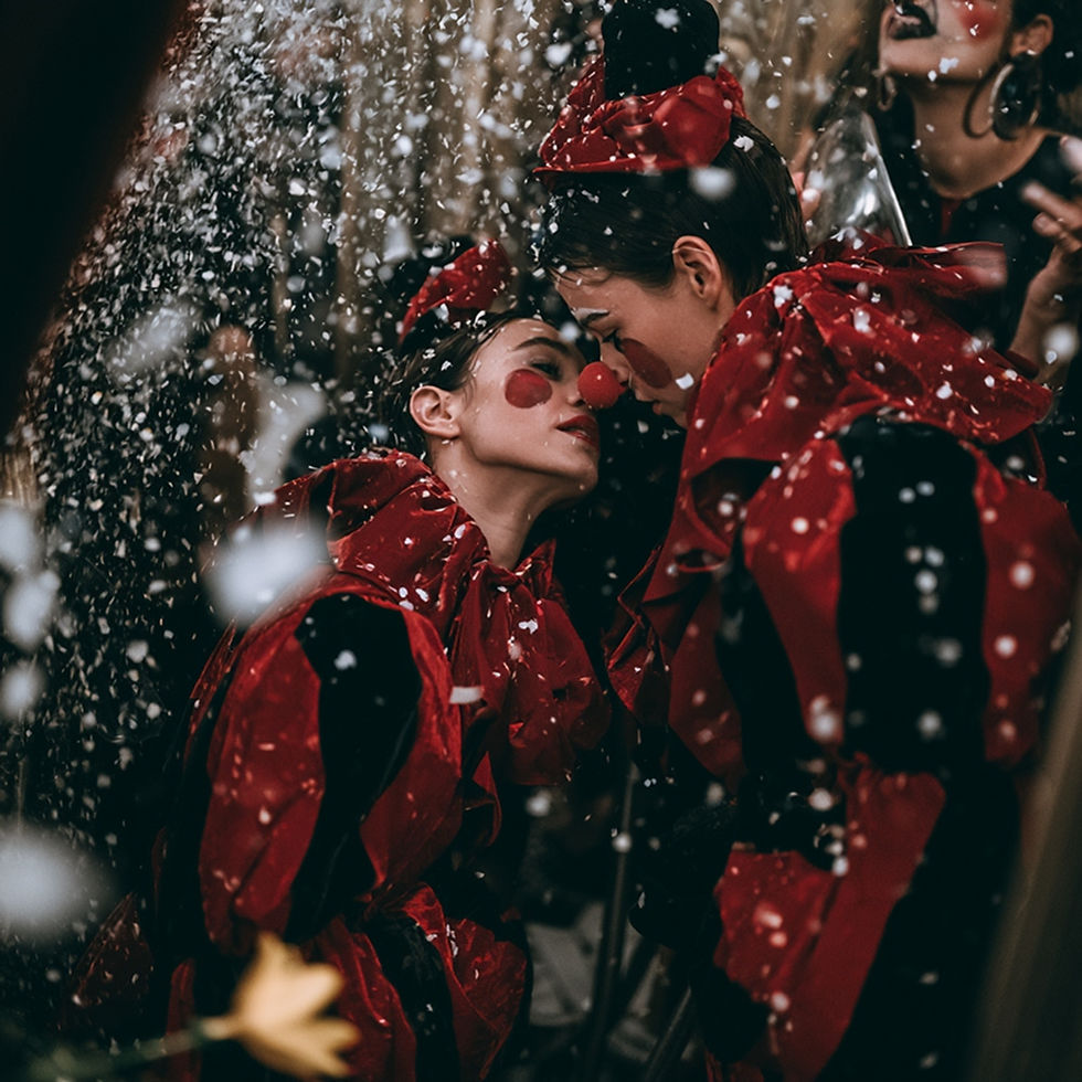 Two stylish adult clown performers backstage as a confetti cannon fires accidentally