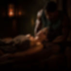 Woman receiving a massage on a brown towel, dimly lit spa setting with warm lighting. Relaxed mood.
