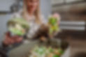 Woman throwing vegetable cuttings in a compost bucket in kitchen and feeding dog..jpg