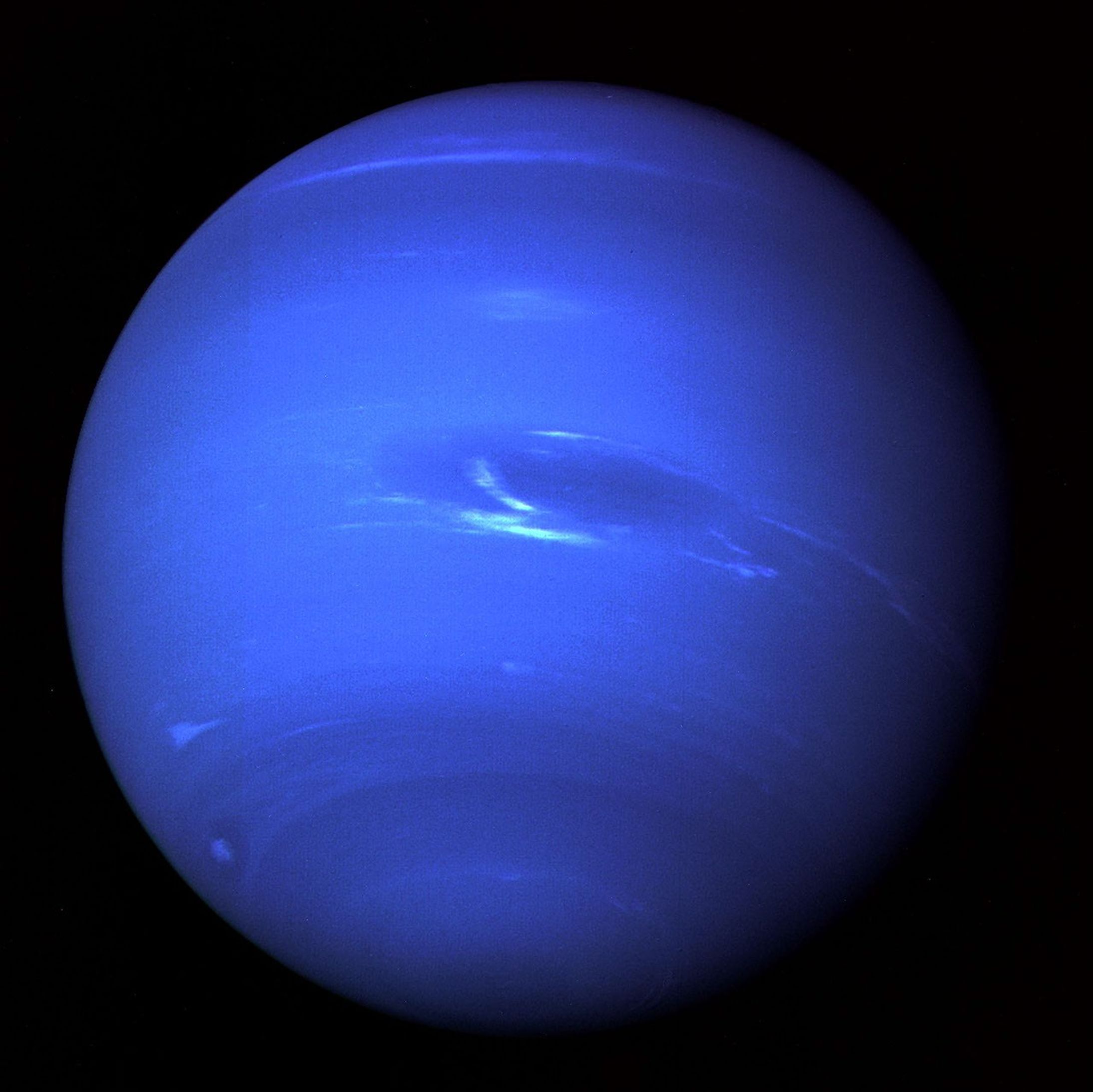 Voyager 2 processed-color view of Neptune in 1989 showing bright clouds and the historical Great Dark Spot.