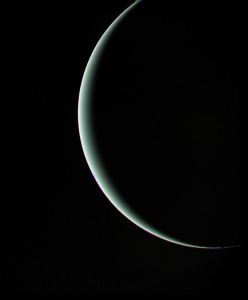 Voyager 2 view of pale blue-green Uranus as a thin crescent while departing in January 1986.