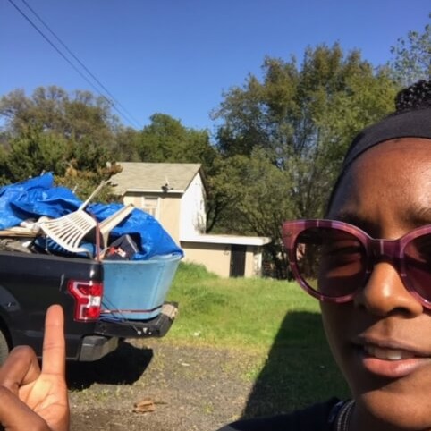 a woman with the back ground pile of garbage