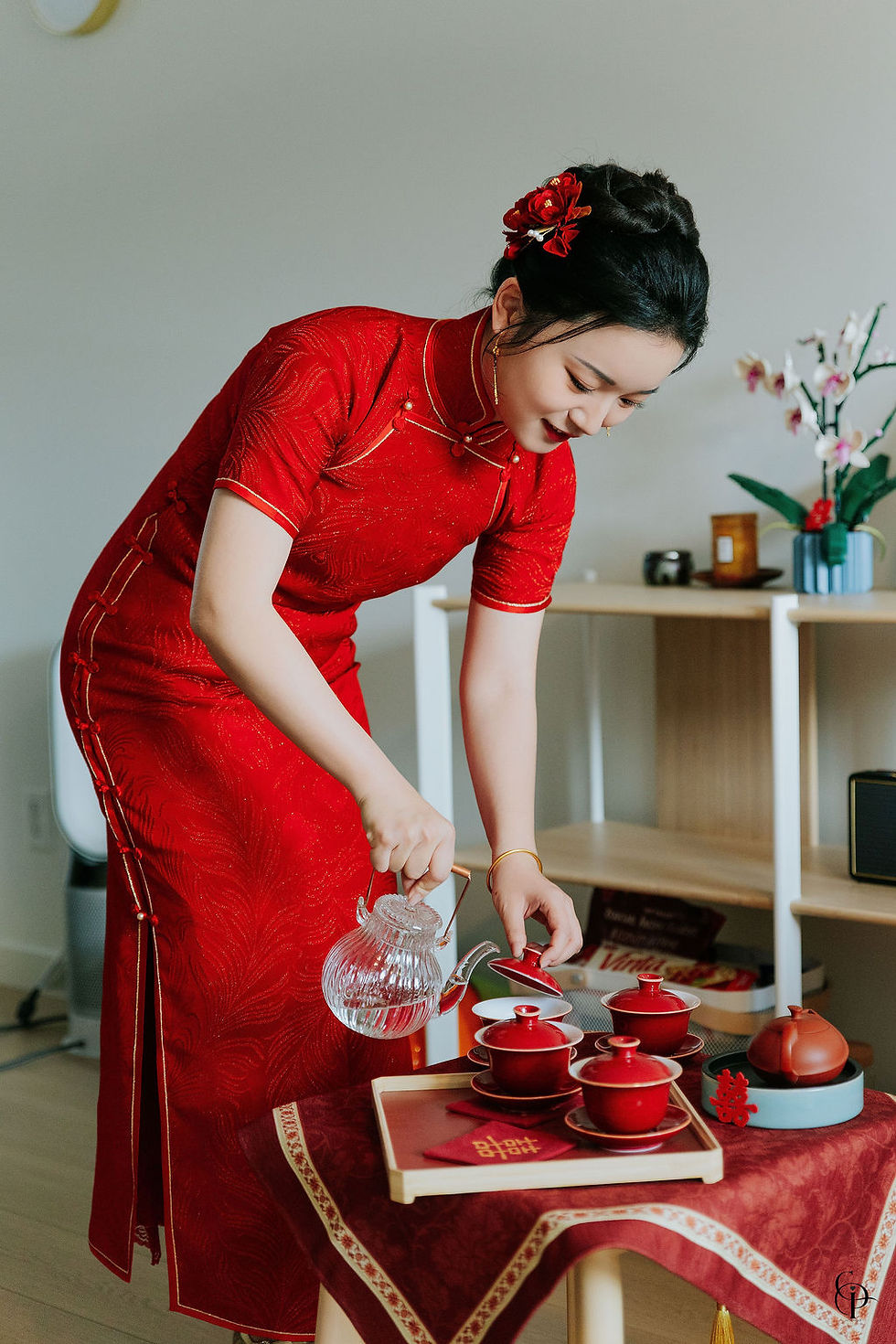 Bride in red qipao pouring tea during a Cantonese wedding tea ceremony