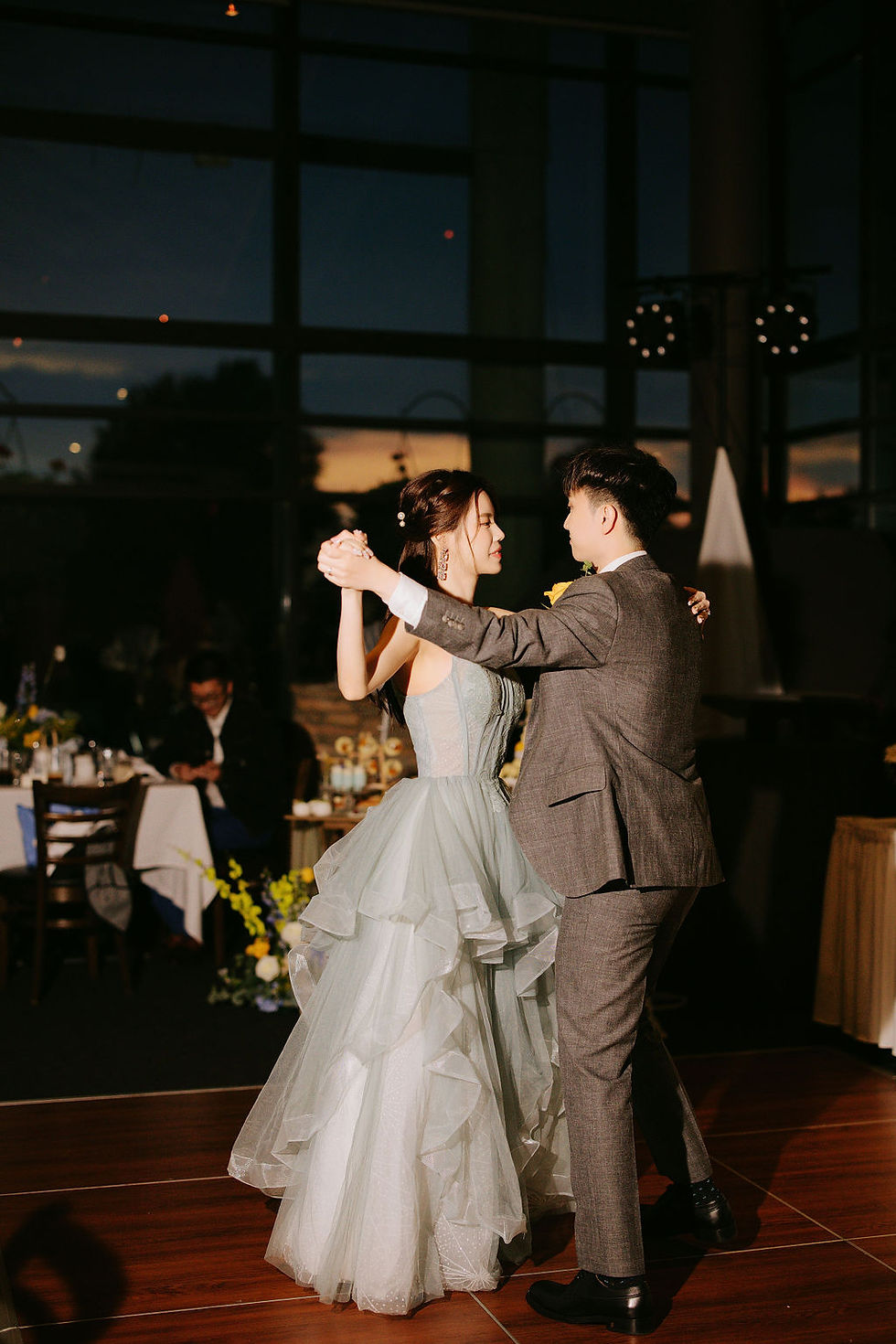 Bride and groom embracing during their indoor wedding reception at Mayfair Lakes, surrounded by blue and yellow floral decorations.