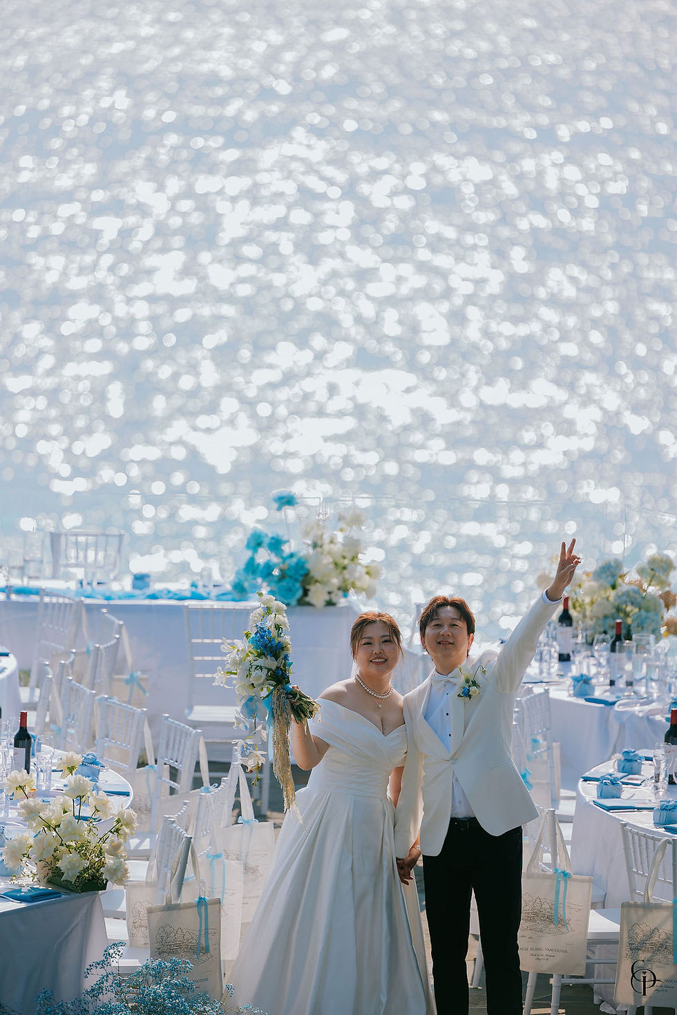 Bride and groom playfully flashing peace signs at the camera with the ocean and wedding decor in the background — joyful Eagle Island wedding moment on Vancouver Island.