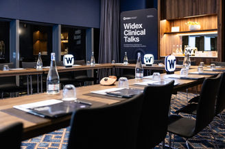 Sala em hotel de luxo com mesas corridas onde irá decorrer evento