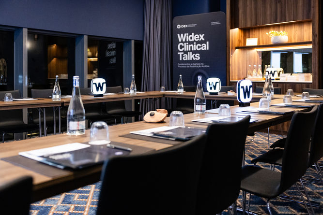 Sala em hotel de luxo com mesas corridas onde irá decorrer evento
