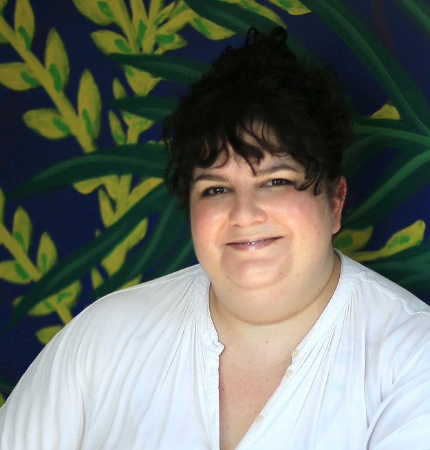 A woman with dark hair sits in from a mural