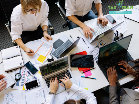 Business professionals reviewing financial reports and tax planning documents during a strategic meeting for small business finances.