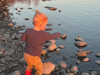 A red-headed toddler throwing rocks in the river