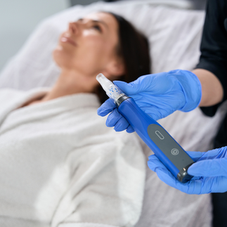A woman holding a skinpen microneedling device and a woman lying in the spa