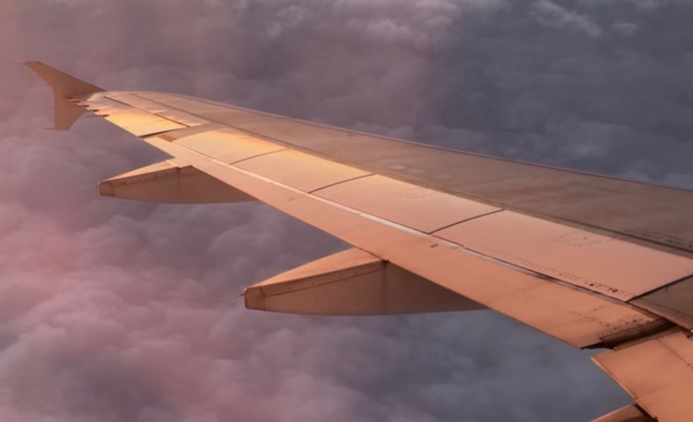 Plane wing over clouds at sunset