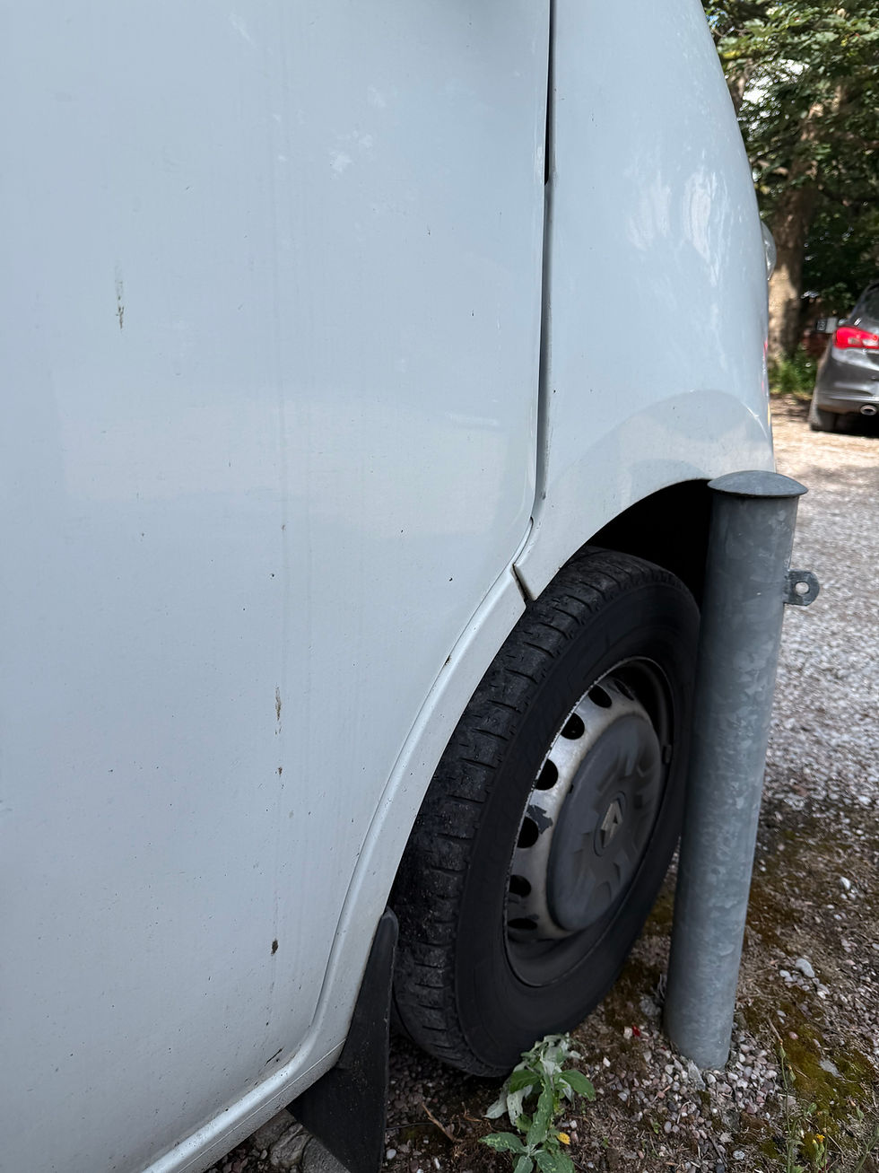 A large rental van is parked within millimetres of a metal bollard.