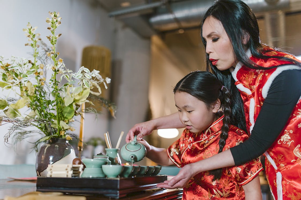 A mother is helping her daughter pour into a cup, with flowers on the table