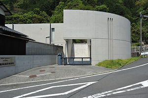 緑豊かな山を背景にした円形のコンクリート造りの建物