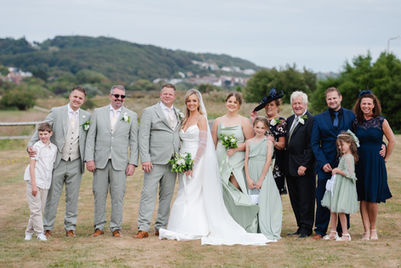 Bride, groom and wedding party posing together on the lawn at Hythe Imperial Hotel, Kent.