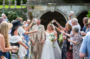 Bride and groom walking through confetti with wedding guests at Mount Ephraim Gardens Kent.