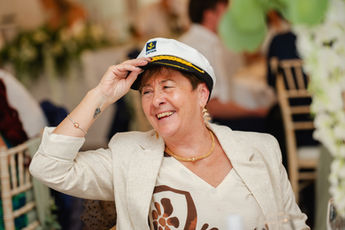Smiling wedding guest tipping a captain’s hat at Hythe Imperial Hotel, Kent.