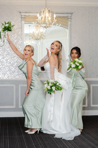 Bride and bridesmaids raising bouquets in the Elizabeth Room at Hythe Imperial Hotel.