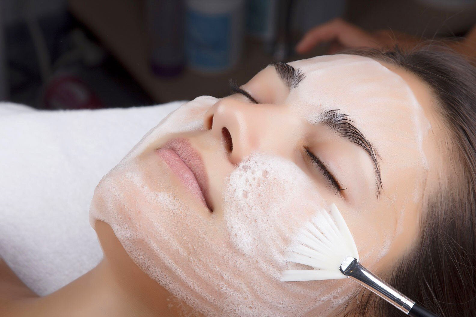 Жінка отримує догляд за обличчям, нанесення пінної маски пензлем