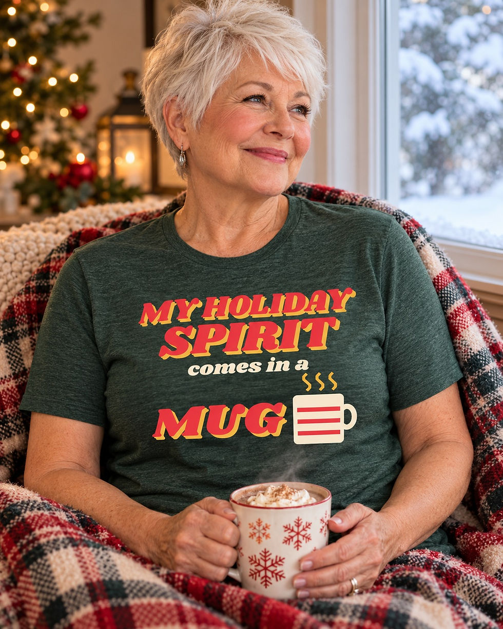 Smiling older woman by a snowy window holding cocoa, wearing the My Holiday Spirit Comes in a Mug funny Christmas t-shirt