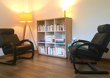 L'image montre la salle de psychothérapie adulte , lumineuse et confortable avec deux fauteuis en cuir inclinables, et uen bibliothéque garnie de nombreux ouvrages de psychologie et de psychanalyse