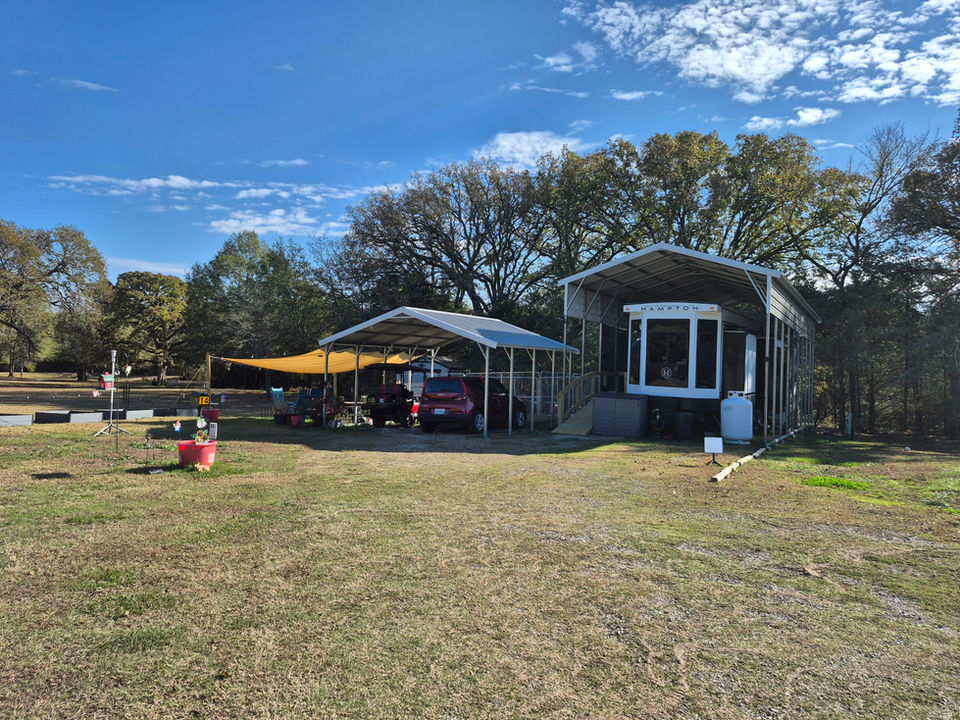Cars parked under covers on a sunny day near trees HOME 4 Rivers Hideaway