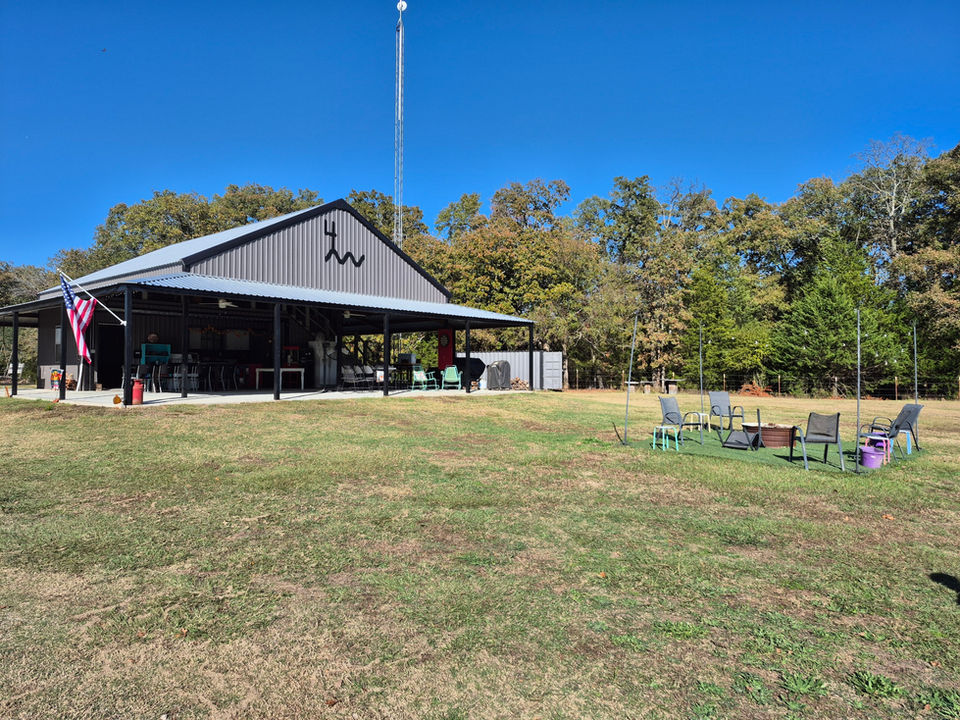 Covered pavilion on green lawn, trees, and blue sky background at 4 Rivers Hideaway