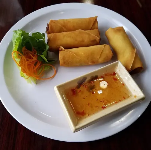 盘子里有炸春卷,配有蔬菜和酱汁,美味可口 Roku sushi and pho