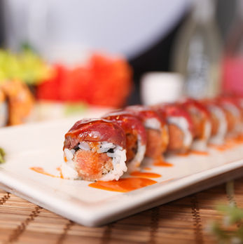 美味寿司卷置于白色餐盘上，旁边酱汁，诱人的寿司美味佳肴。