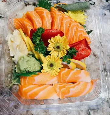 Fresh salmon sashimi arranged with ginger, flowers, and wasabi; kamiya sushi.
